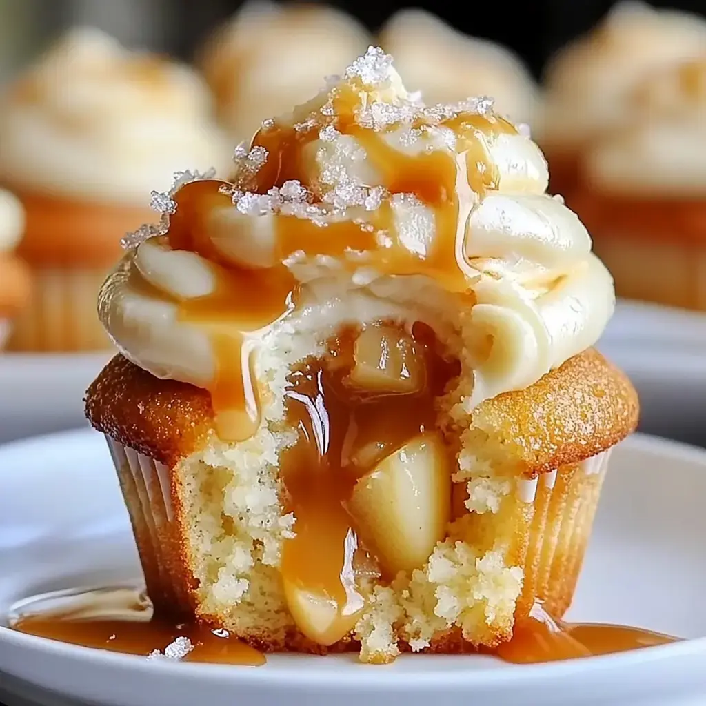 Close-up on a cupcake with creamy frosting, gooey honey drizzle, and peach filling visible in the bite.