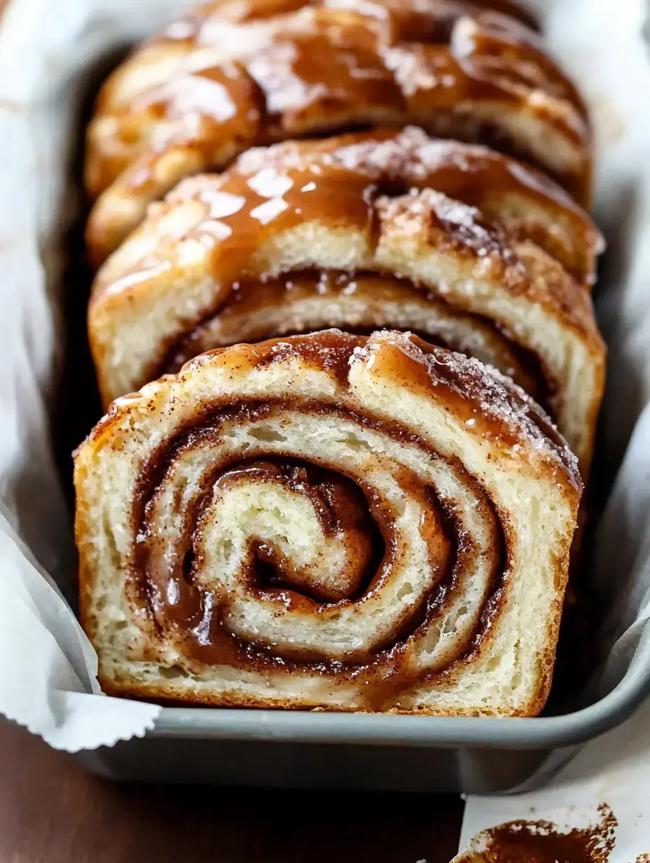 A close-up view of sliced cinnamon roll bread drizzled with icing.