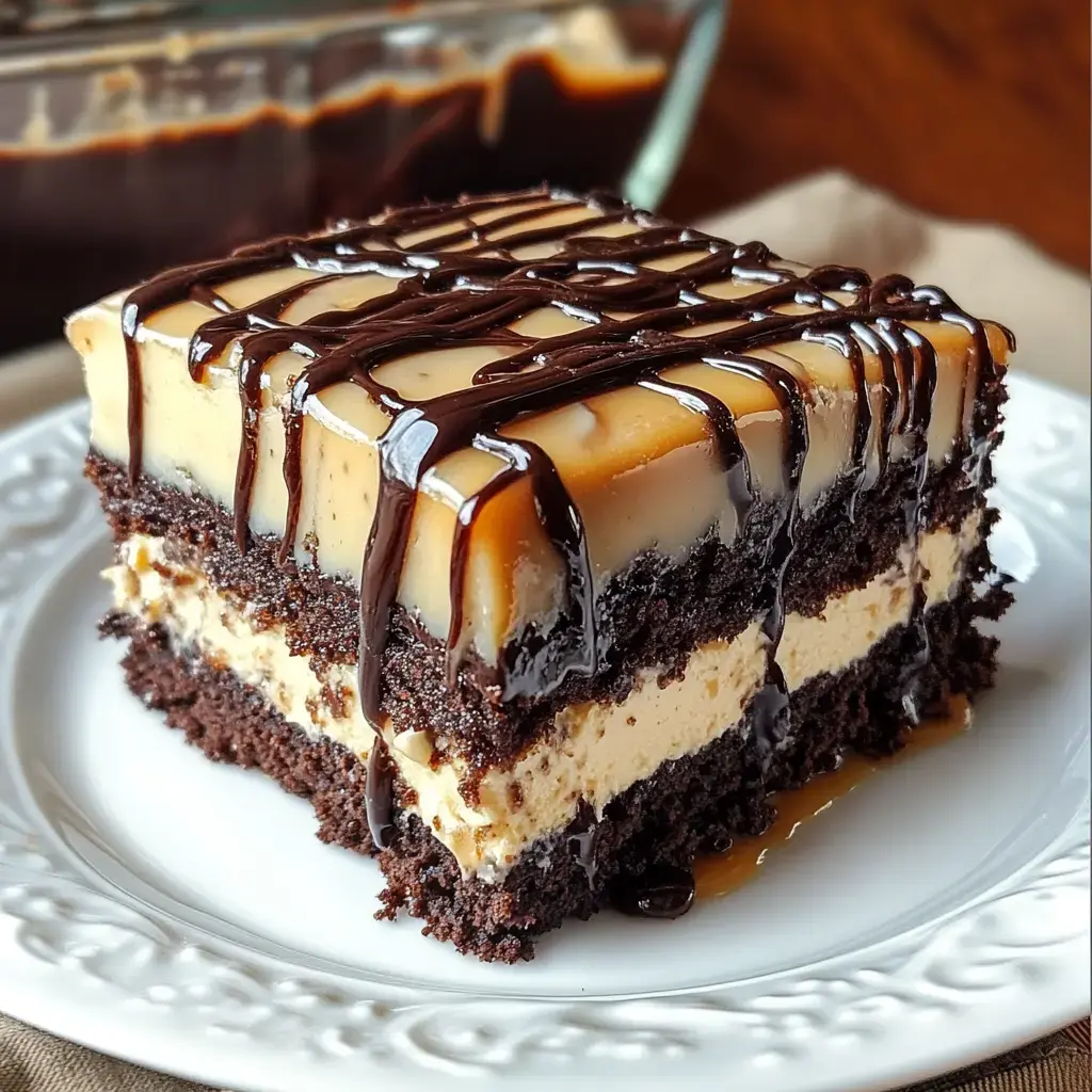 A delicious slice of chocolate cake layered with gooey caramel and topped with shiny chocolate and caramel drizzle on a white plate.
