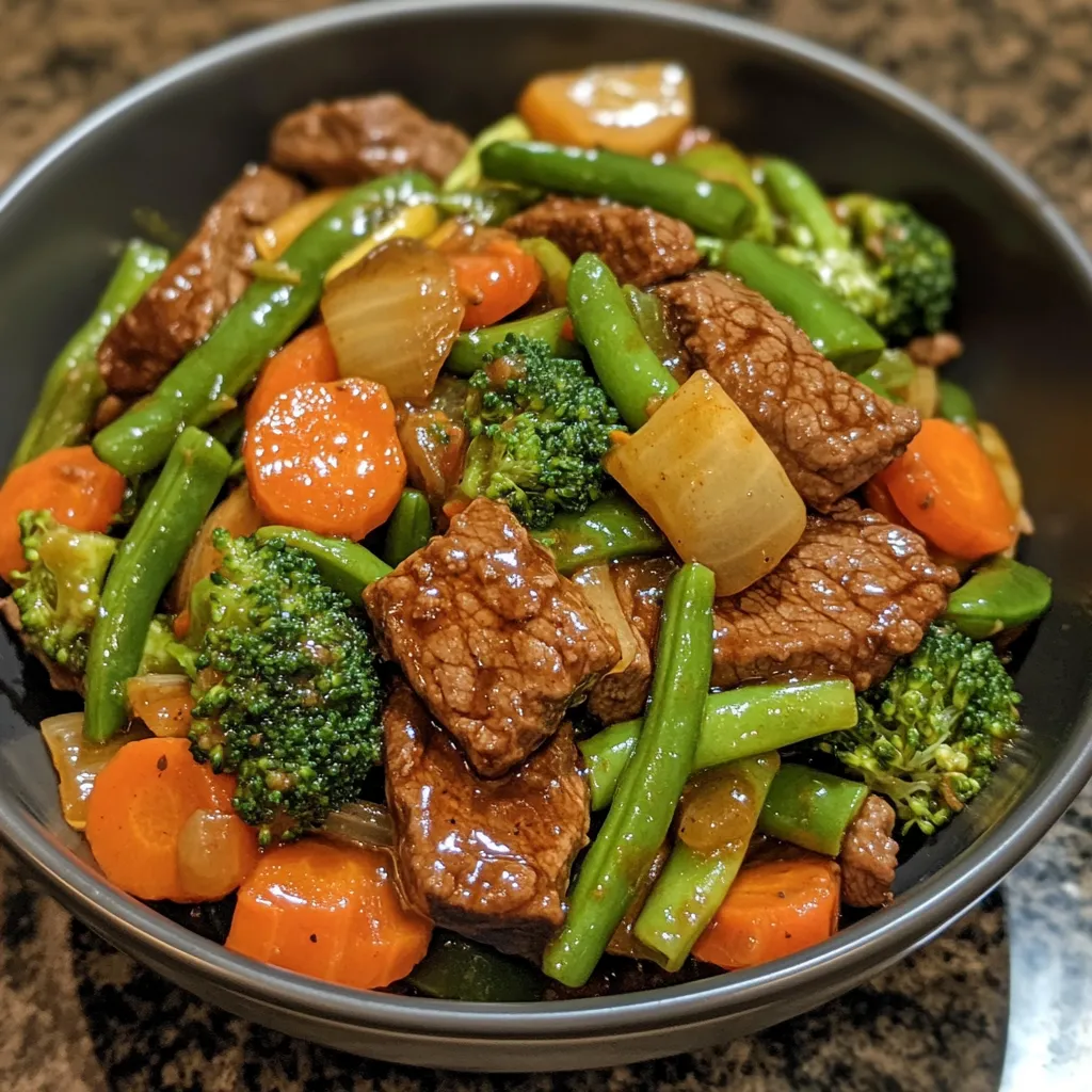 A bowl of beef and vegetables, including carrots and broccoli, sits on a table.