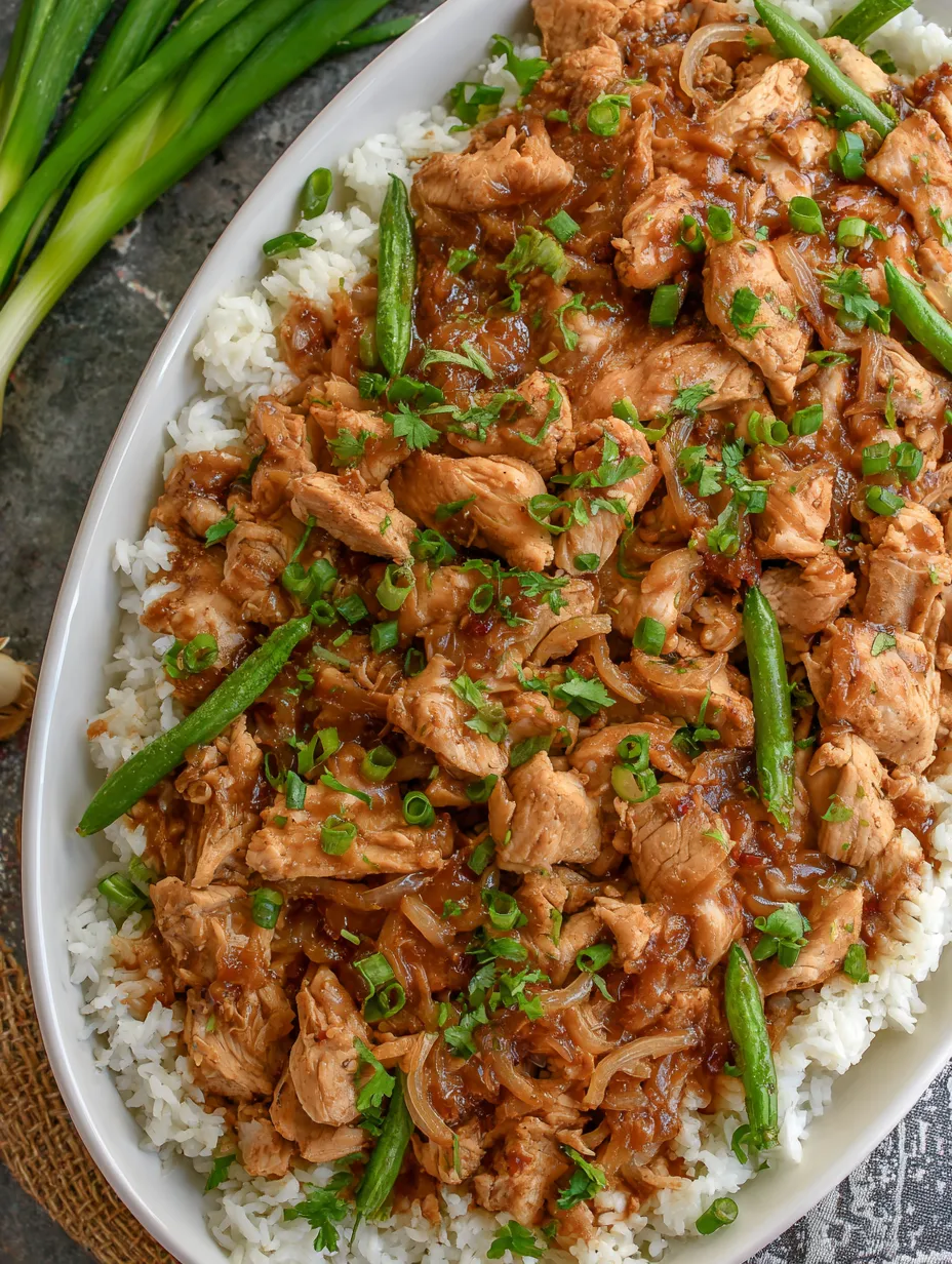 A white plate filled with a mix of rice, chicken, and onions.